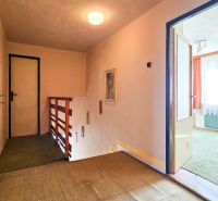 Flur in einem Einfamilienhaus mit Holzgeländer, offenen Türen und Teppichboden.