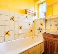 Ein Badezimmer in einem Einfamilienhaus mit Sonnenblumenfliesen und gelben Wänden.