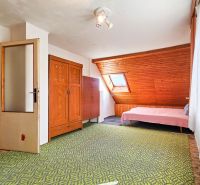 Ein Zimmer in einem Einfamilienhaus mit Holzelementen, einem Bett und einem grünen Teppich.