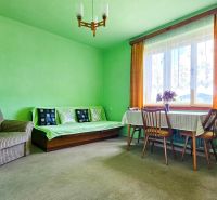 Wohnzimmer in einem Einfamilienhaus mit einem bequemen Sessel, einem Sofa und einem runden Tisch.
