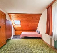 Dachbodenschlafzimmer in einem Einfamilienhaus mit Holzwand und gemustertem Teppich.