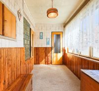 Ein Flur in einem Einfamilienhaus mit Holzverkleidung und einem großen Fenster mit Spitzenvorhängen.