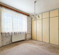 Ein Zimmer in einem Einfamilienhaus mit Teppichboden, Einbauschrank und zarten Blumenmustertapeten.