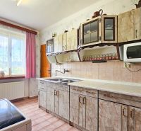 Küche in einem Einfamilienhaus mit buntem Vorhang, Fliesen und Küchenzeile.