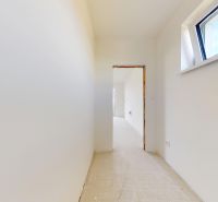 Ein schmaler Flur in einem Einfamilienhaus mit weißen Wänden und einem Dachfenster.