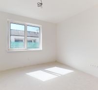 Ein geräumiges Zimmer in einem Einfamilienhaus mit einem großen Fenster, weißen Wänden und freiliegender Beleuchtung.