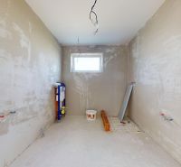 Unvollendetes Badezimmer in einem Einfamilienhaus mit Fenster und Vorbereitung für die Installation von Sanitäranlagen.
