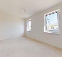 Ein geräumiges, helles Zimmer in einem Einfamilienhaus mit weißen Wänden und großen Fenstern.