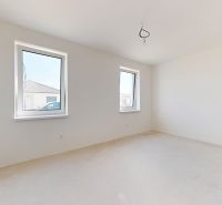 Helles Zimmer in einem Einfamilienhaus mit zwei Fenstern und weißen Wänden.