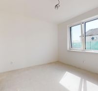 Helles Zimmer im Einfamilienhaus mit großem Fenster, unfertiger Boden, weiße Wände.