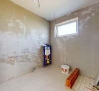 Ein im Bau befindliches Badezimmer in einem Einfamilienhaus, mit vorbereiteter Installation und einem Eimer Farbe.