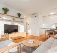 Wohnzimmer in einer 2-Zimmer-Wohnung mit Holzboden und hellen Möbeln.
