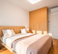 Schlafzimmer mit Doppelbett, Kleiderschrank und Holzboden in einer 2-Zimmer-Wohnung.