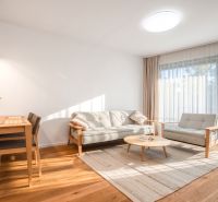 Helles Wohnzimmer mit Holzboden, Sofa und Esstisch.