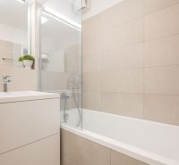 Badezimmer mit Badewanne und Waschbecken in einer 2-Zimmer-Wohnung, helle Fliesen.