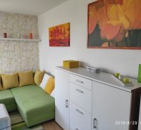 Wohnzimmer mit Sofa, Holzboden, dekorative Bilder und Kerzen.