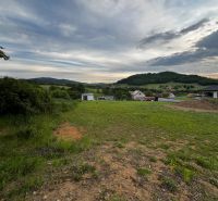 Grünflächen und hügelige Landschaft im Hintergrund der Wohngebiete in Stožok.