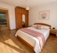 Schlafzimmer in einer 3-Zimmer-Wohnung mit Holzboden und pastellfarbenen Elementen.
