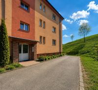 Ein Wohnhaus in Istebné mit grüner Umgebung und blauem Himmel, ideal für eine 3-Zimmer-Wohnung.