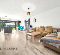 Wohnzimmer in einem Einfamilienhaus mit Holzboden und großen Fenstern zum Garten.