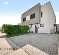 Ein Einfamilienhaus in Hrubá Borša mit gepflastertem Parkplatz und gepflegtem Grünbereich.