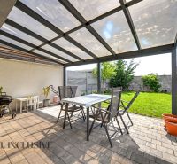 Überdachte Terrasse mit Sitzbereich und Grill neben einem Einfamilienhaus in Hrubá Borša.