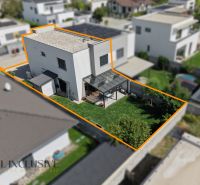 Ein Einfamilienhaus in Hrubá Borša mit Terrasse und Rasen im Garten, getrennt durch einen orangefarbenen Ausschnitt.