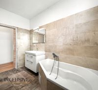 Badezimmer mit Badewanne und Waschbecken in einem Einfamilienhaus mit Fliesen in Beigetönen.