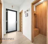 Der Flur in einem Einfamilienhaus mit Holzelementen und Fotos an der Wand.