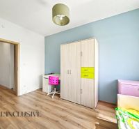 Ein Zimmer in einem Einfamilienhaus mit einem Boden in Holzoptik, Möbeln und farblichen Details.