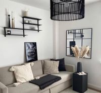 Wohnzimmer in einem Einfamilienhaus mit bequemer Couch, dekorativen Regalen und modernem Kronleuchter.