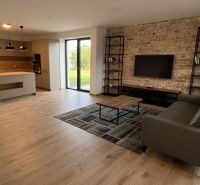 Wohnzimmer mit Küche in einem Einfamilienhaus mit Holzboden und Ziegelwand.