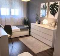 Ein Zimmer in einem Einfamilienhaus mit einem Boden in Holzoptik, Kunstgemälden und dekorativen Blumen.