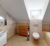 Badezimmer mit Badewanne und Waschbecken, Boden mit Holzdekor, schräges Dach.