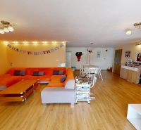 Wohnzimmer mit einem orangefarbenen Sofa, einem Esstisch und einem Boden mit Holzdekor.