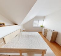 Schlafzimmer in einem Einfamilienhaus mit Holzboden und schräger Decke.