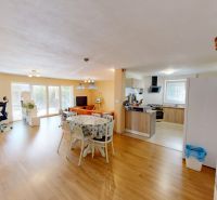Helles Wohnzimmer mit Holzboden und Küche in einem Einfamilienhaus.