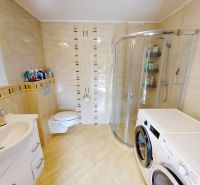 Badezimmer in einem Einfamilienhaus mit Waschbecken, Dusche, Waschmaschine und Trockner.