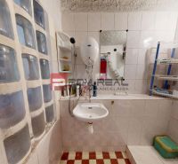 Badezimmer in der Hütte mit Waschbecken, Dusche und Regalen für Hygieneartikel.