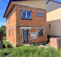 Unvollendetes Einfamilienhaus in Cerová mit sichtbaren Ziegelwänden und Kunststofffenstern.