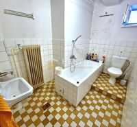 Badezimmer mit Badewanne und Fliesenboden in einem Einfamilienhaus.