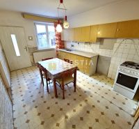 Küche in einem Einfamilienhaus mit Esstisch, hellen Schränken und Gasherd.