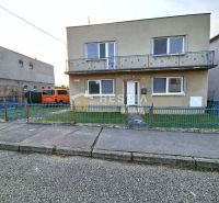 Ein Einfamilienhaus in Senica mit einem Balkon, einem blauen Zaun und einem geparkten Auto.