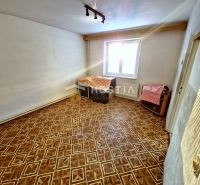 Ein Zimmer in einem Einfamilienhaus mit Holzboden, weißen Wänden und einem Fenster.