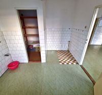 Küche mit weißen Fliesen und offener Speisekammer in einem Einfamilienhaus.