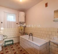 Badezimmer mit gefliester Badewanne und Boiler in einem Einfamilienhaus.