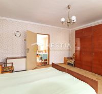 Schlafzimmer in einem Einfamilienhaus mit Retro-Möbeln und gemusterten Tapeten an der Wand.