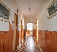Ein Flur in einem Einfamilienhaus mit Oberflächen in Holzdekor und gemustertem Boden.