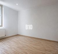 Ein Zimmer in einer 3-Zimmer-Wohnung mit einem Boden in Holzoptik und weißen Wänden.