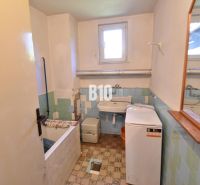 Ein Badezimmer in einem Einfamilienhaus mit Waschmaschine, Badewanne und Waschbecken, gefliest mit bunten Fliesen.